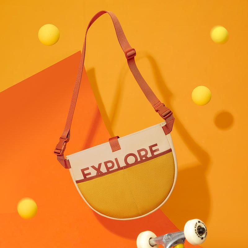 Stylish explore print crossbody bag with adjustable strap, vibrant orange background, and skateboard wheels