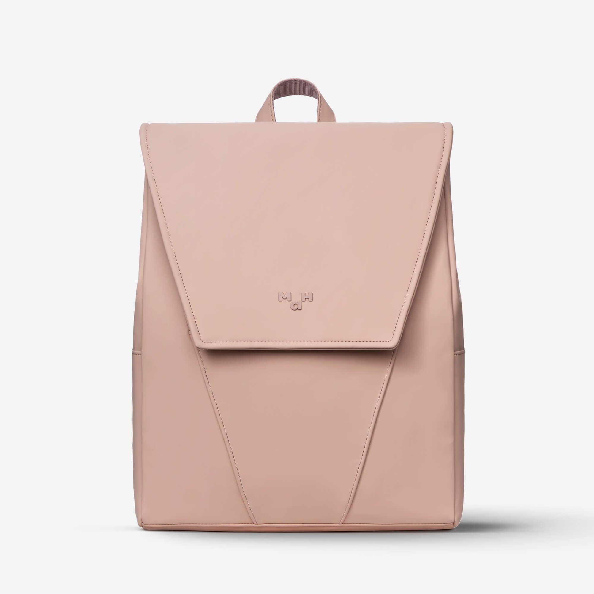 Blush pink minimalist backpack with flap closure and subtle branding, ideal for everyday use or travel.