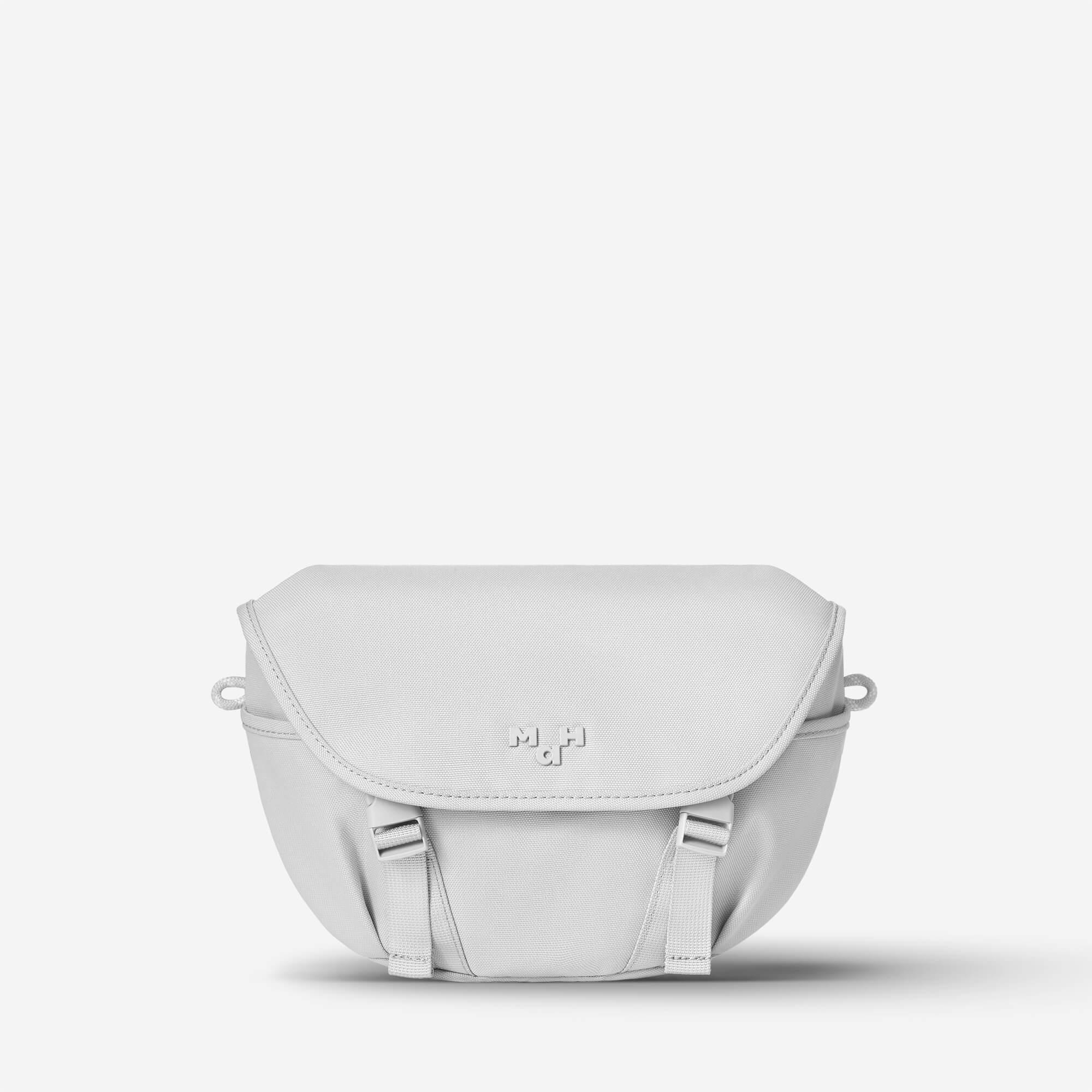 Light gray minimalist crossbody bag with flap closure and adjustable straps, ideal for everyday use.