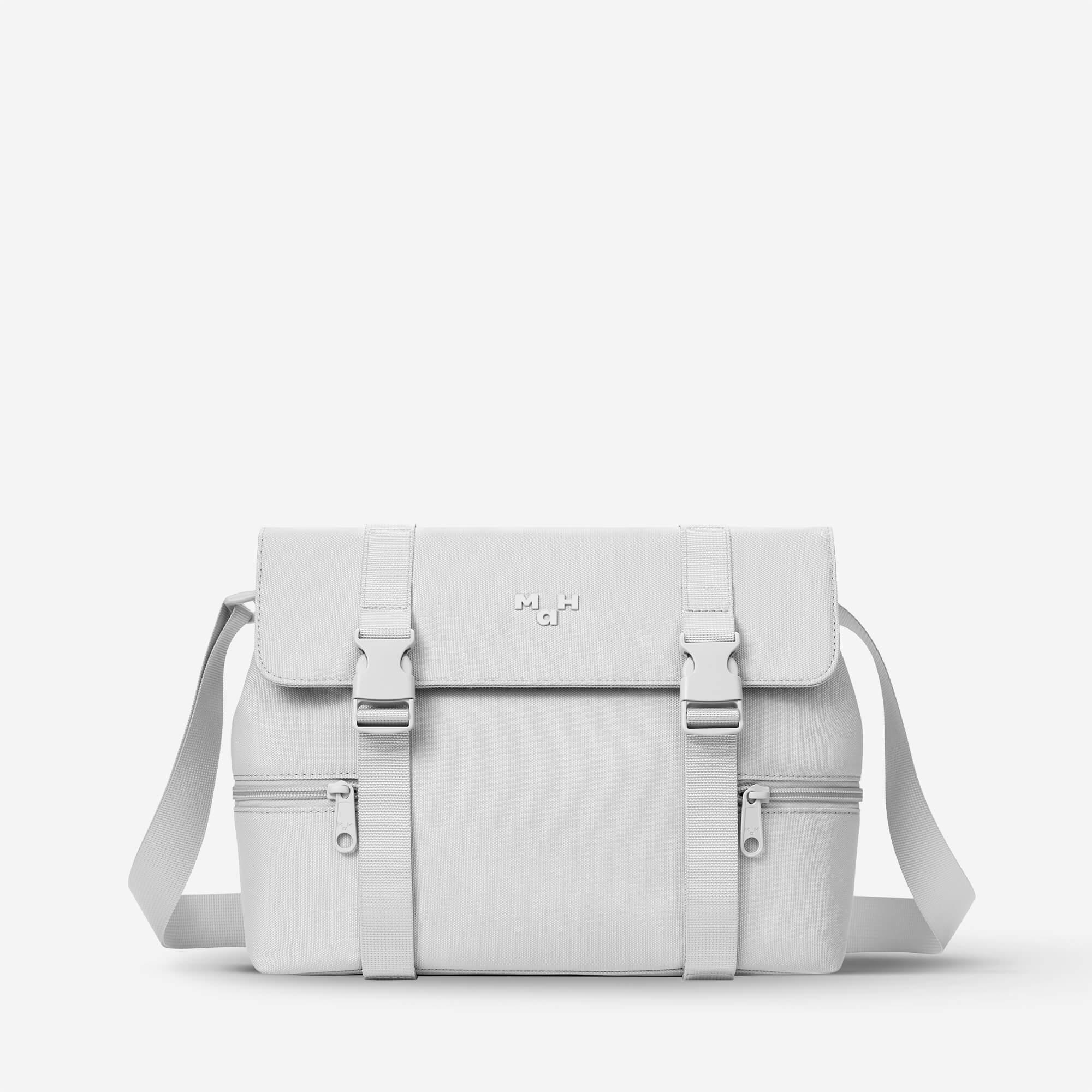White minimalist satchel bag with adjustable straps and front pockets, ideal for everyday carry and travel.