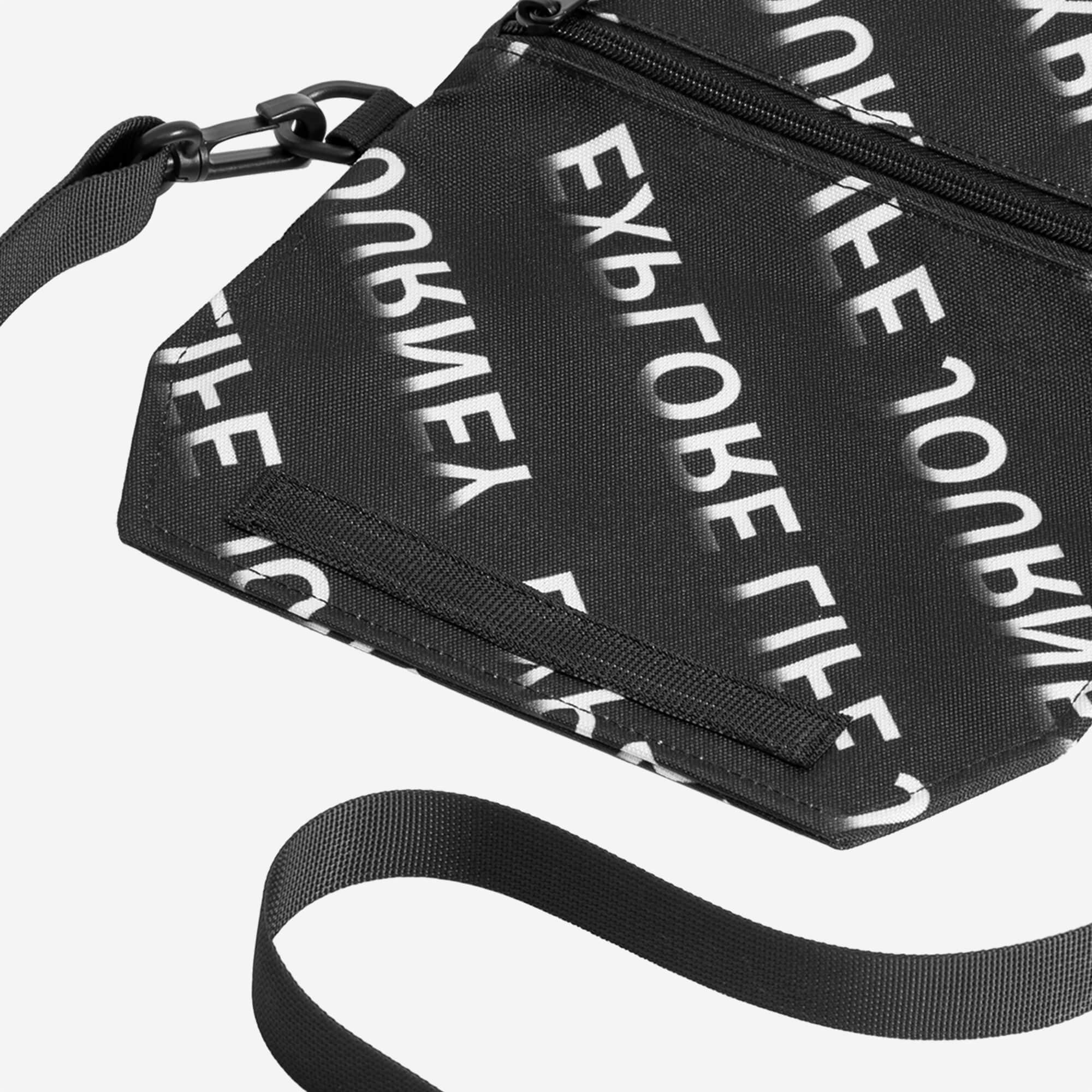 Black crossbody bag with 'Explore Life Journey' print, adjustable strap, and zipper closure