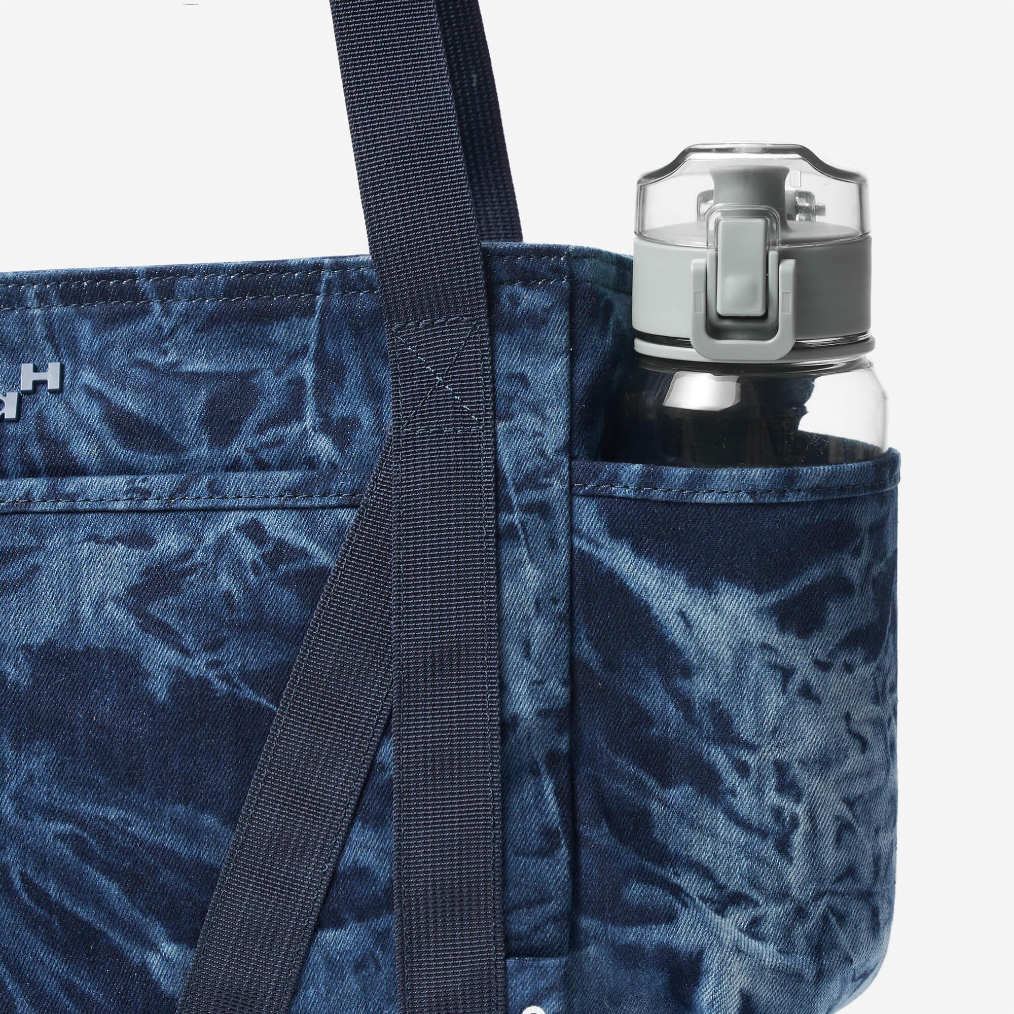 Blue tie-dye tote bag with side pocket holding water bottle, featuring durable straps and stylish design.