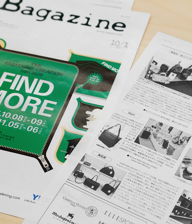 Green 'Find More' pouch with zipper, displayed with magazine and product catalog featuring bags and accessories.