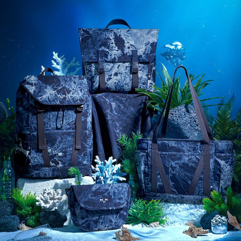 Marble-patterned backpacks, tote, and pouch in underwater scene with coral and aquatic plants