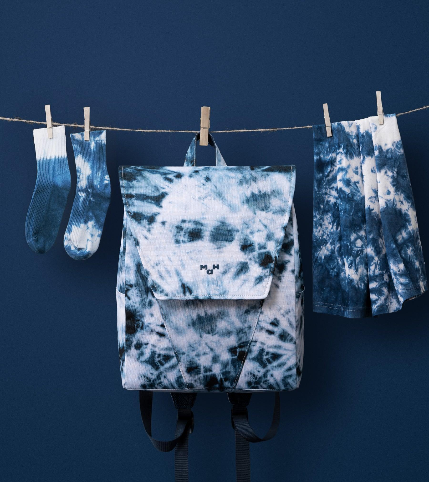 Blue tie-dye backpack with matching socks and shorts hanging on a clothesline against dark blue background