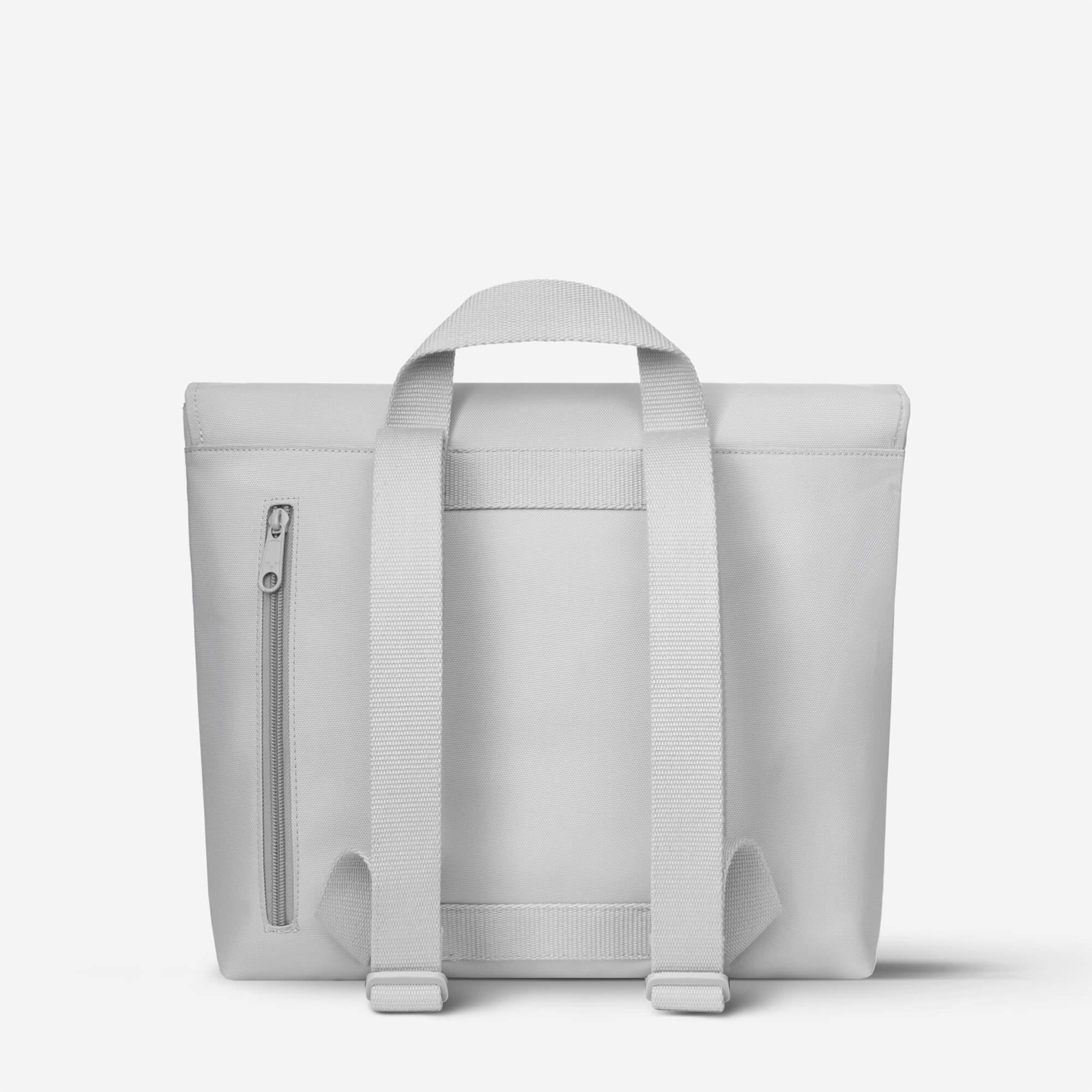 Light gray minimalist backpack with top handle and side zip pocket, ideal for daily use or travel