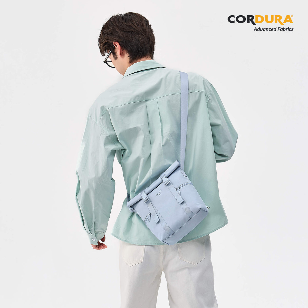 Light blue crossbody bag with adjustable strap, worn by man in mint shirt, made with Cordura fabric