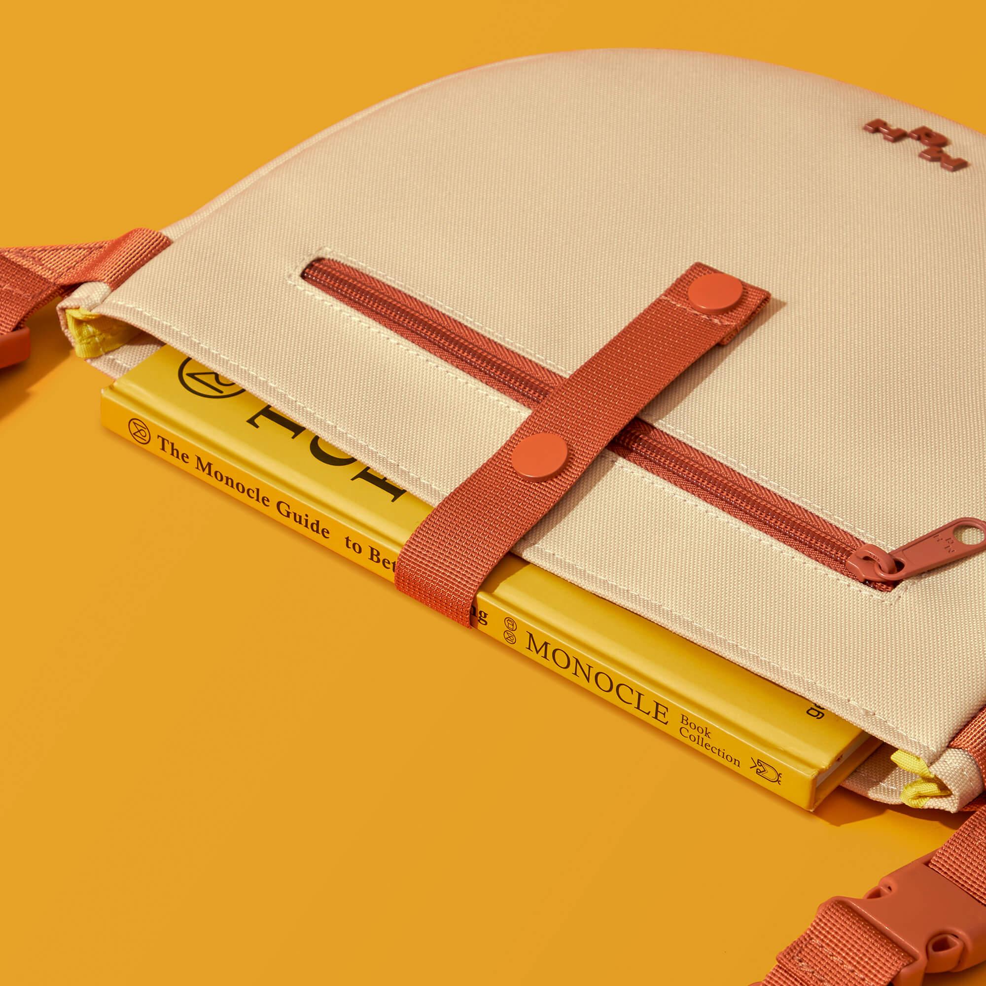 Beige canvas bag with rust straps holding Monocle books, stylish everyday accessory for urban lifestyle