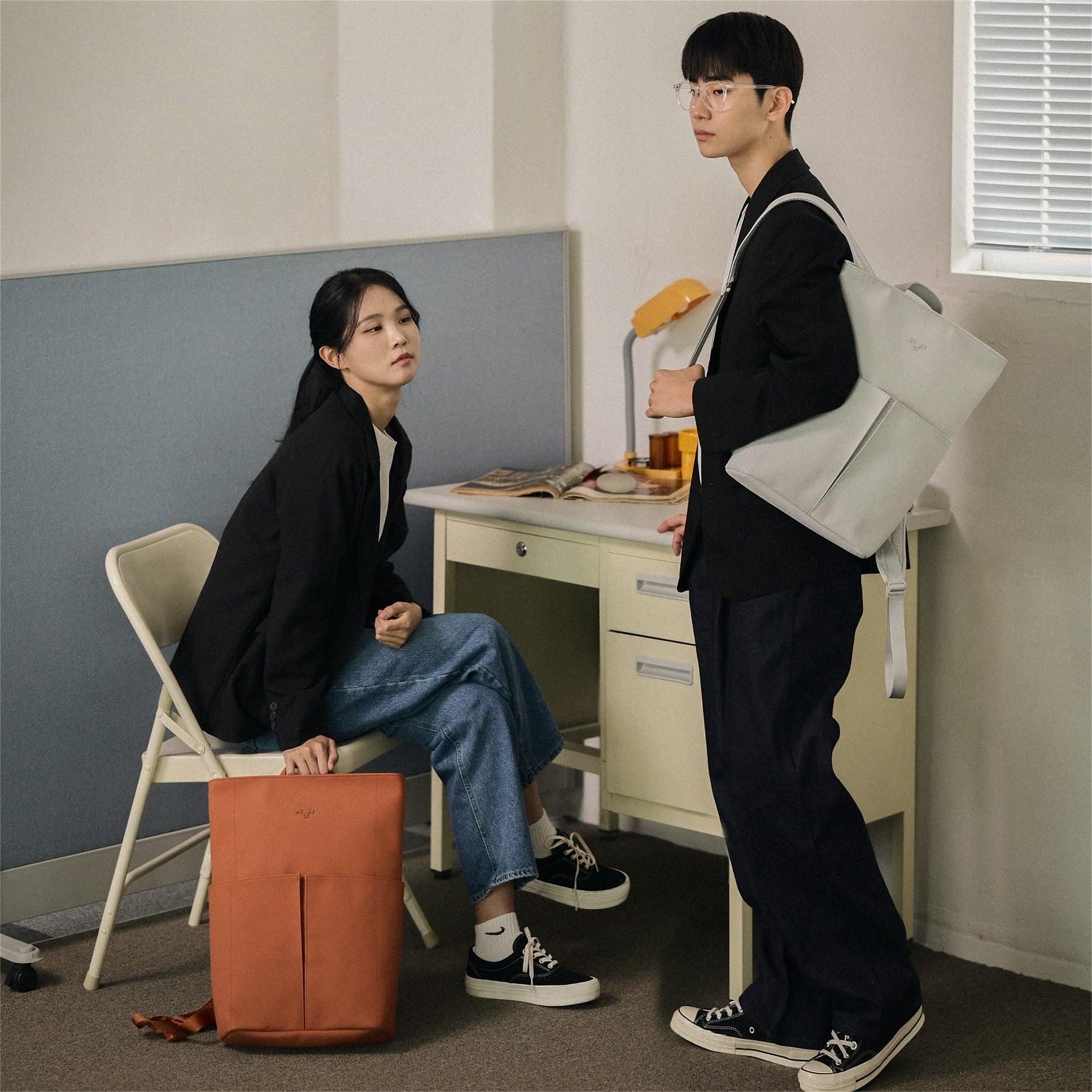 Man and woman with stylish backpacks in office setting, modern design, everyday carry
