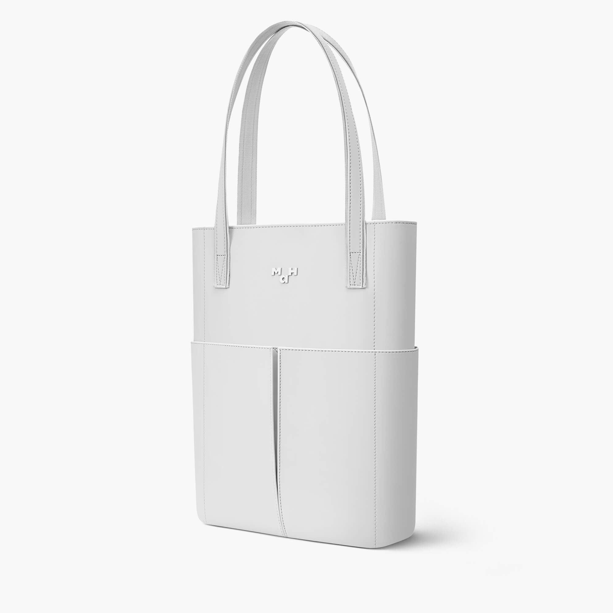 White minimalist tote bag with front pockets and dual handles, sleek design for everyday use