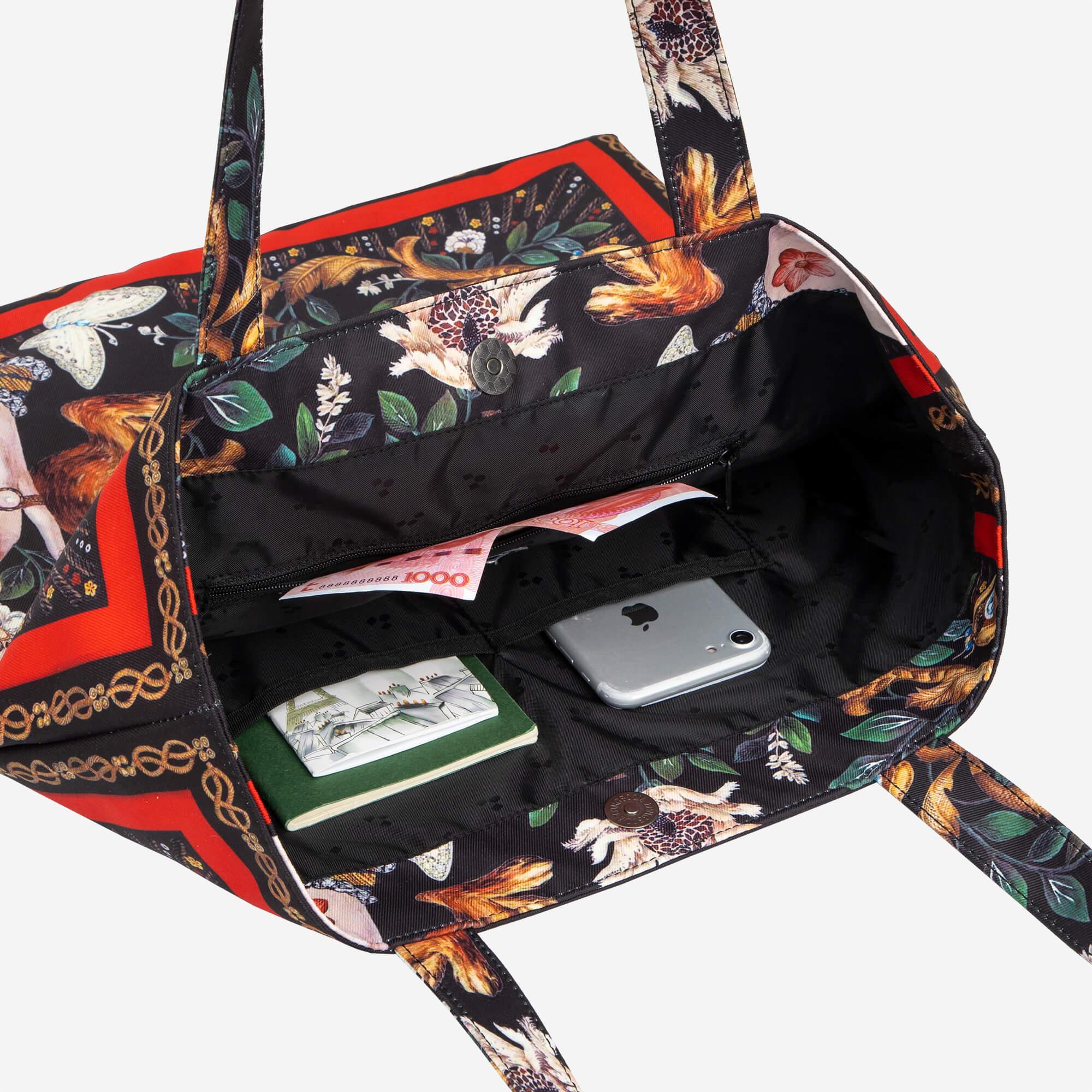 Floral print tote bag with interior pockets holding phone, cash, and notebook