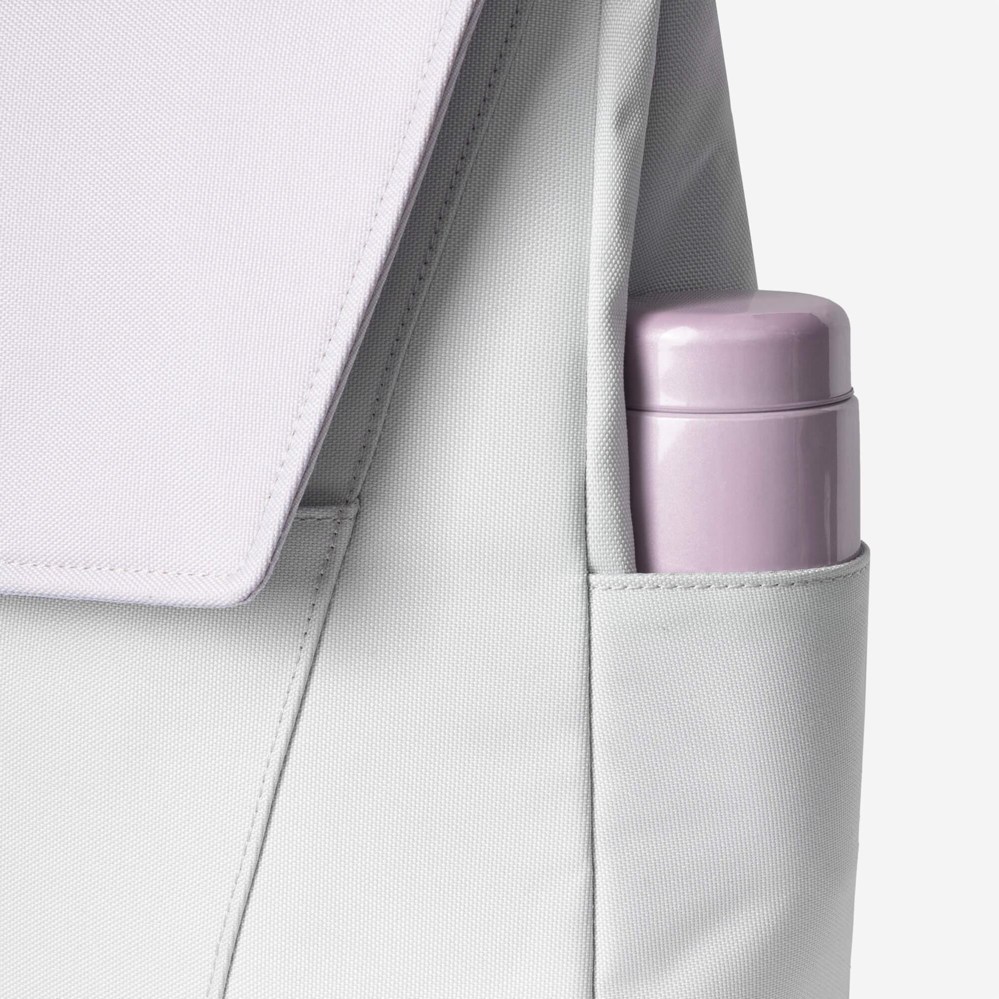 Light gray backpack with side pocket holding a purple water bottle, showcasing functional design and durable fabric.