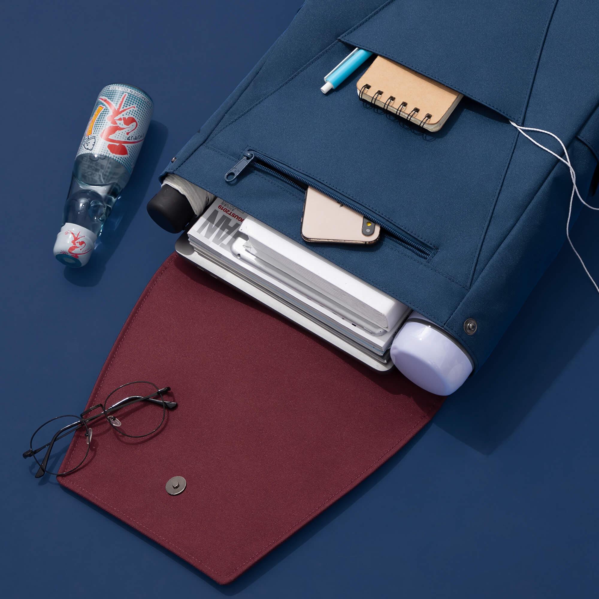 Blue backpack with laptop, notebook, phone, and water bottle on navy background