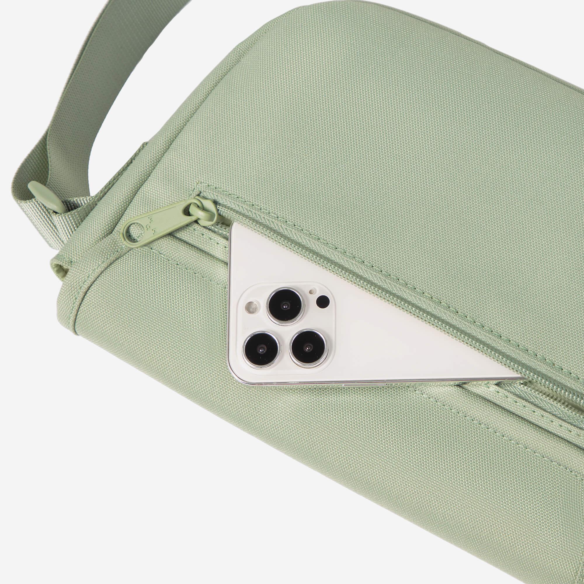 Mint green crossbody bag with phone peeking from front zip pocket, ideal for everyday carry and travel