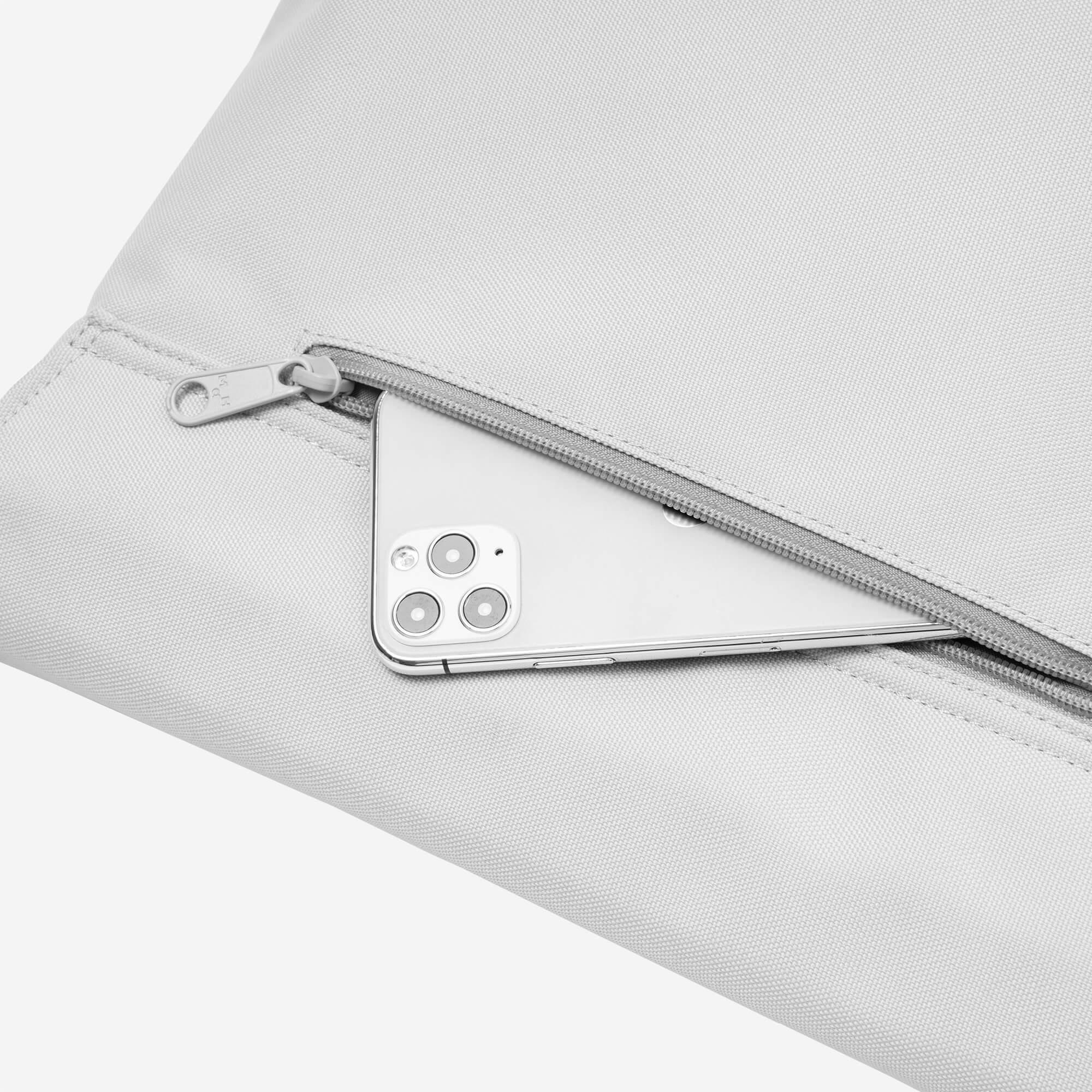 Light gray backpack with zipper pocket holding a smartphone, showcasing sleek design and secure storage.