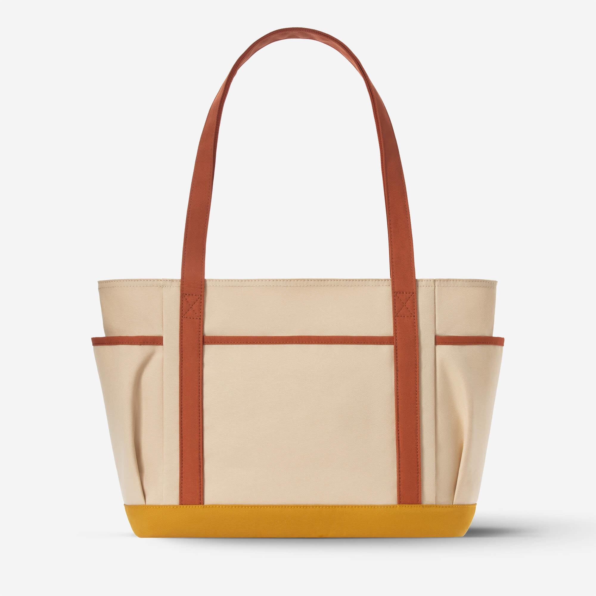 Beige canvas tote bag with rust straps and mustard base, ideal for everyday carry and lifestyle use.