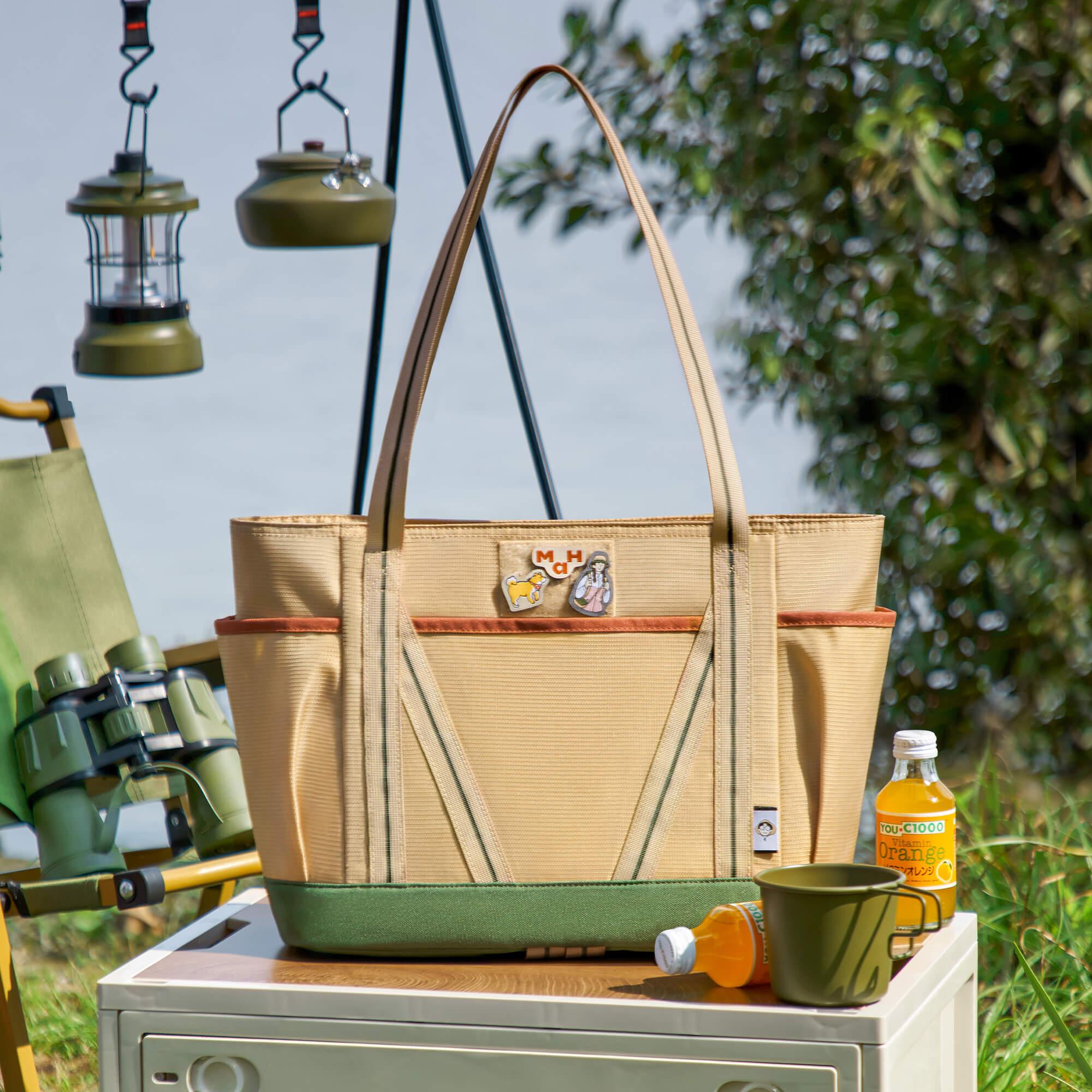Beige canvas tote bag with green base, perfect for outdoor camping, picnics, or travel adventures.