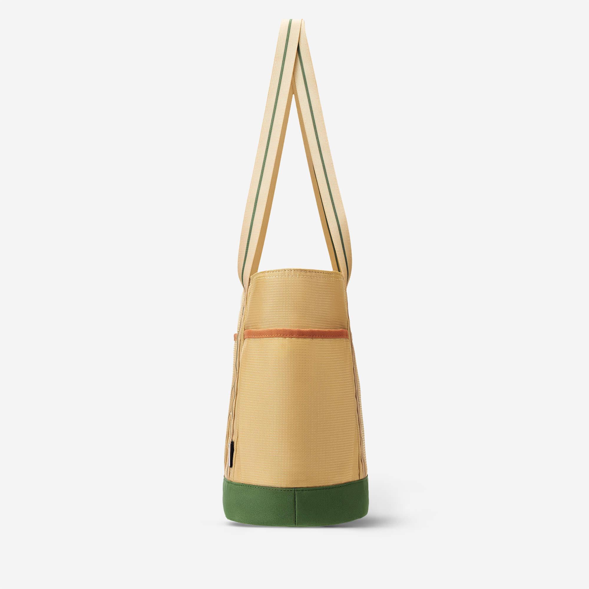 Beige tote bag with green base and striped handles, side view