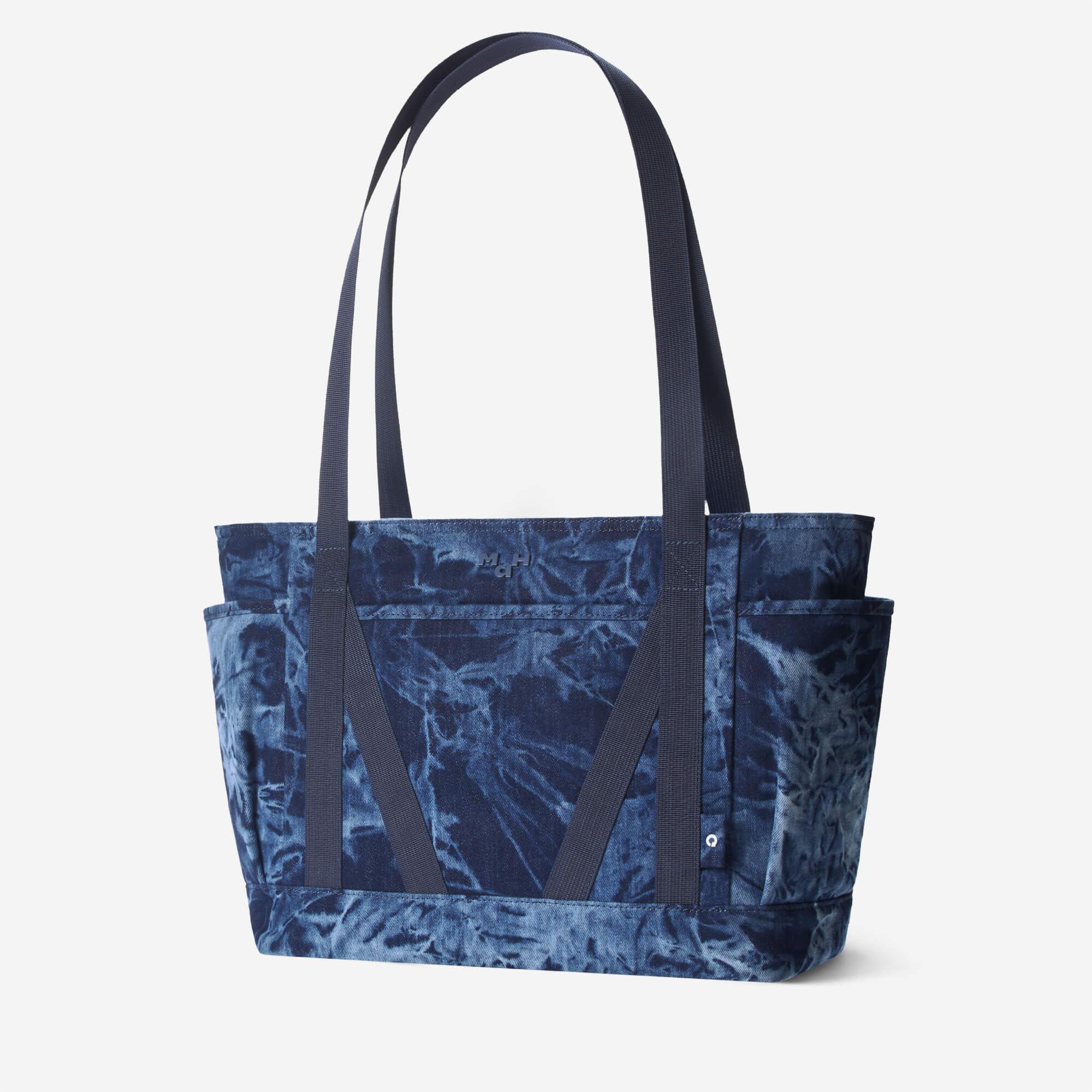 Blue tie-dye tote bag with dual straps and front pockets, ideal for everyday carry and lifestyle use.